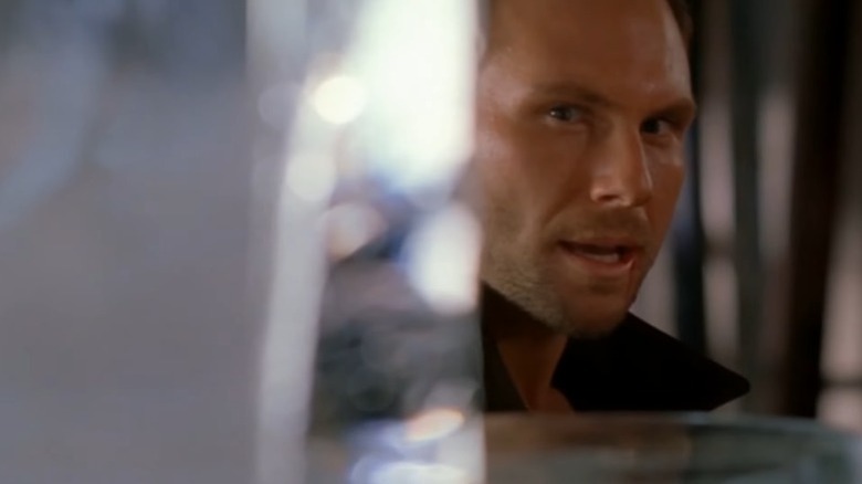 Christian Slater as Edward Carnby peering through a wall opening in Alone in the Dark