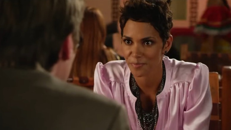 Halle Berry as Emily smiling mischievously at a restaurant table in Movie 43