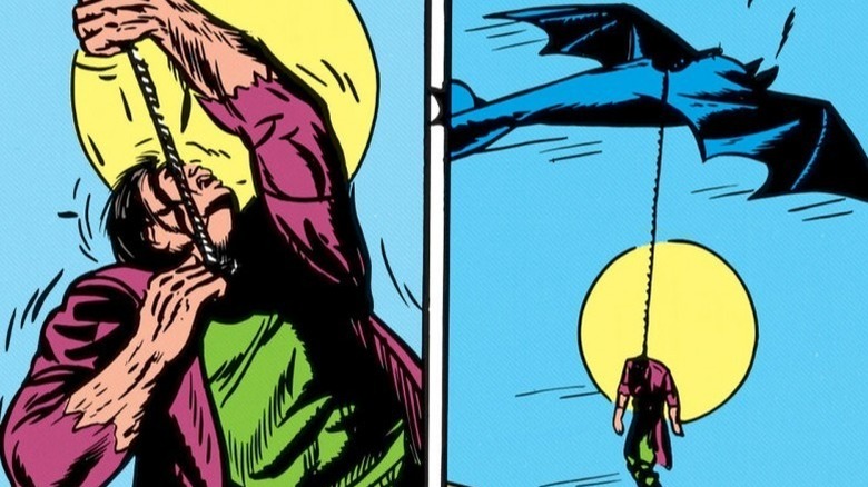 Batman hangs a man from the Batplane