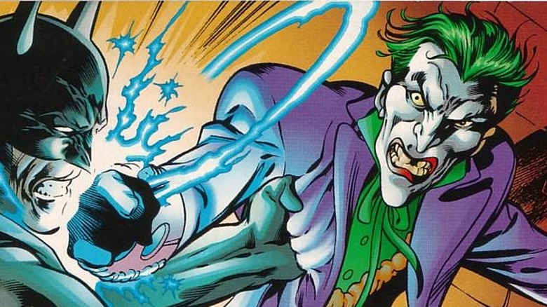 The Joker hits Batman while wearing super power electric gauntlets