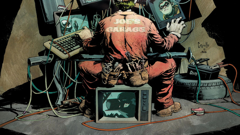 The Joker sits in front of several computer screens watching the Bat-Family