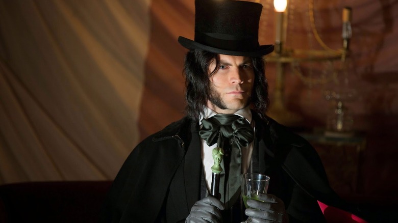 An old-fashioned gentleman with a top hat and cane, holding a glass