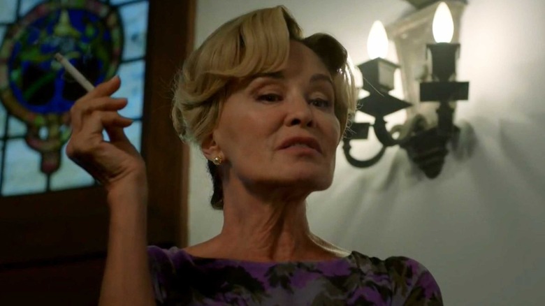Contance looks down condescendingly, holding a cigarette