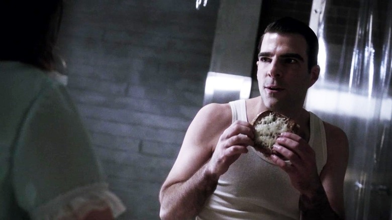 Dr. Thredson sits with a sandwich in his hands, looking at someone offscreen