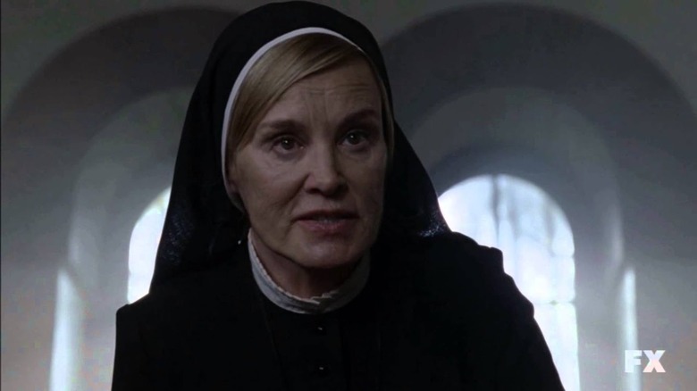 A nun looks forward with a serious expression