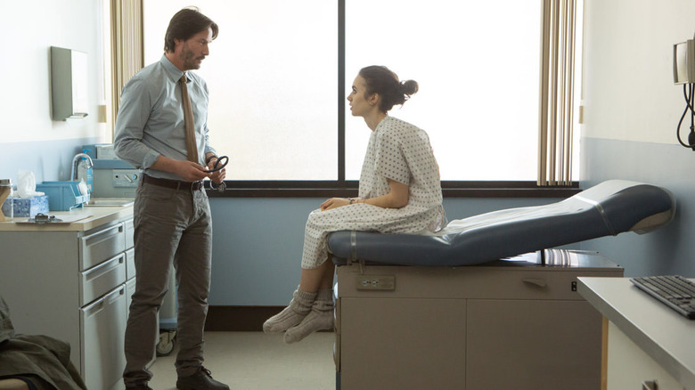 Keanu Reeves talking to Lily Collins, seated
