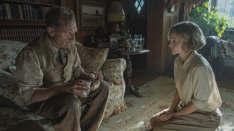 Ralph Fiennes covered in dirt and Carey Mulligan kneeling