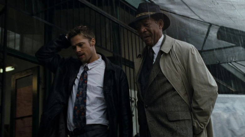 Morgan Freeman, Brad Pitt look over a crime scene in the rain in Se7en