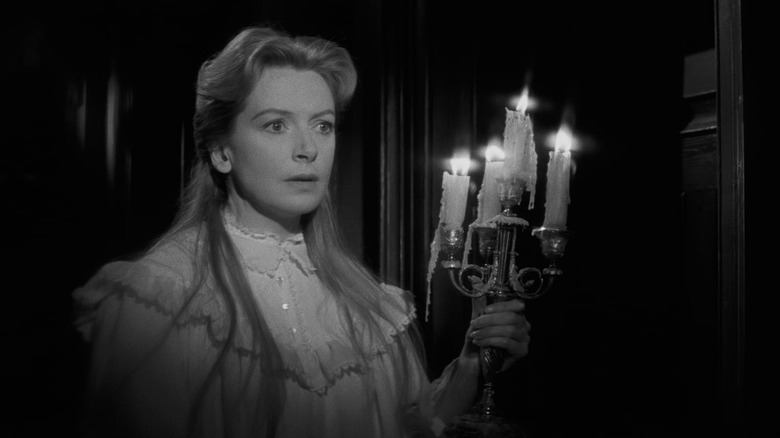 Deborah Kerr holding candles in a dark hall in The Innocents