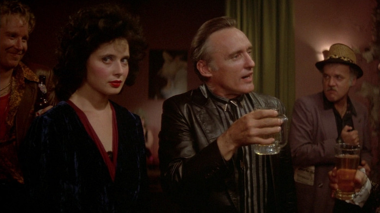 Dennis Hopper as Frank Booth holding a drink while standing next to Isabella Rossellini as Dorothy in Blue Velvet