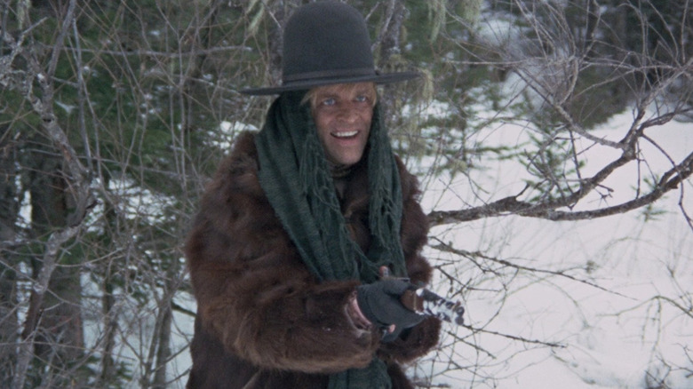Klaus Kinski as Loco Tigrero holding a gun in the wintry woods in The Great Silence