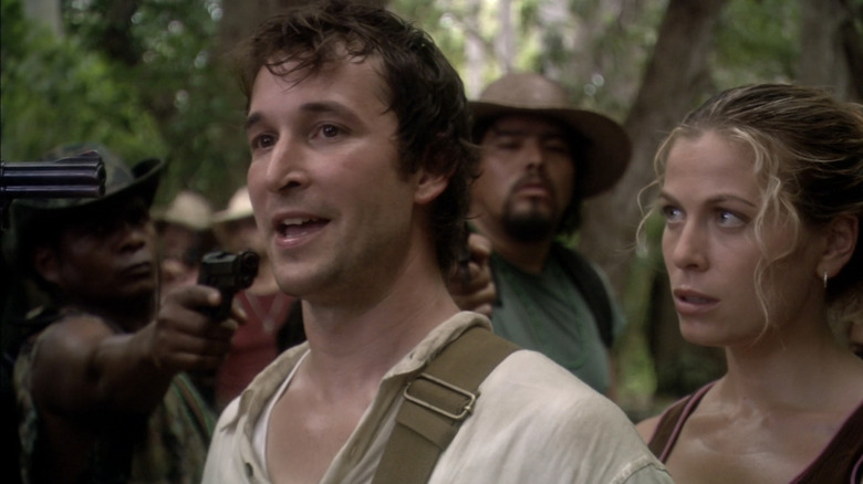 Noah Wyle as Flynn Carsen stands beside Sonya Walger as Nicole Noone while surrounded by guns in The Librarian: Quest for the Spear