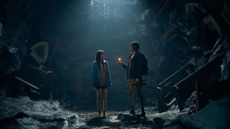 Millie and Tim stand in a cave together
