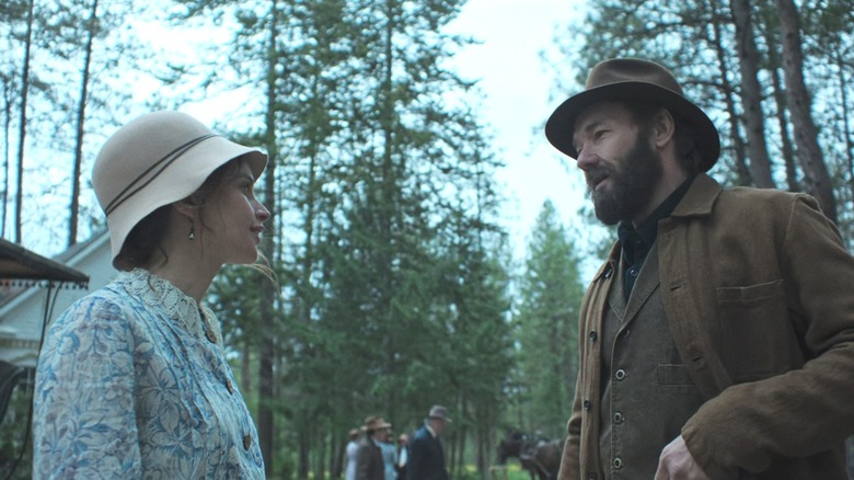 Gladys Olding Grainier de Felicity Jones parle à Robert Grainier de Joel Edgerton à l'extérieur d'une église dans une forêt dans Train Dreams