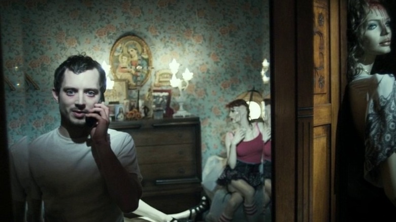 Elijah Wood on the phone surrounded by mannequins