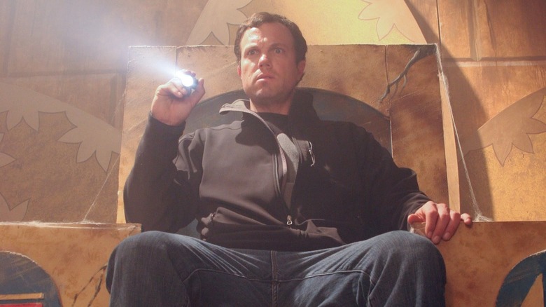 A high-looking Jesse (Adam Baldwin) illuminates the inside of a cardboard pyramid hall with a ten dollar flashlight in Sands of Oblivion