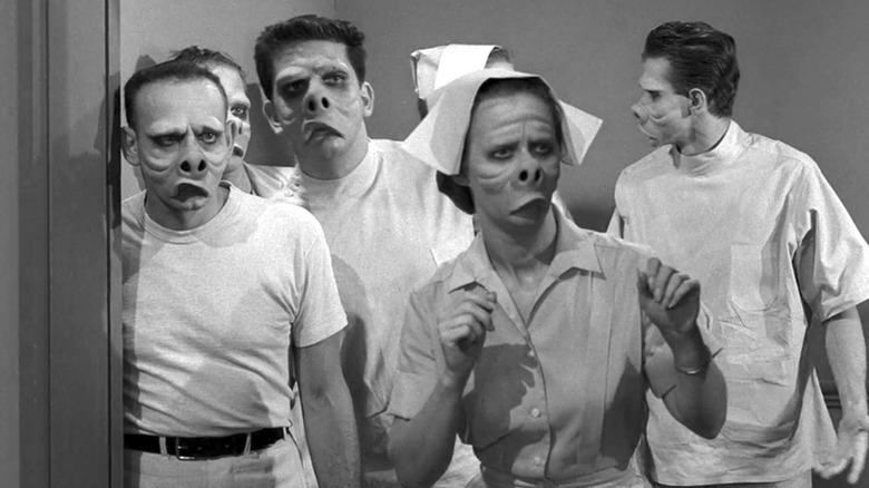 The pig-like hospital staff stand looking at something off-screen in The Twilight Zone episode "Eye of the Beholder"