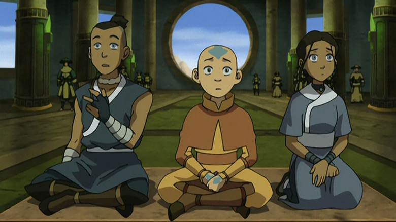 Sokka, Aang, Katara look surprised at something off screen while they're seated in a temple setting in Avatar: The Last Airbender