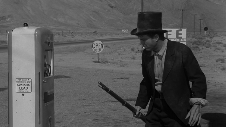 Christian Horn with rifle in hand investigating a gas pump in The Twilight Zone's "A Hundred Yards Over the Rim"