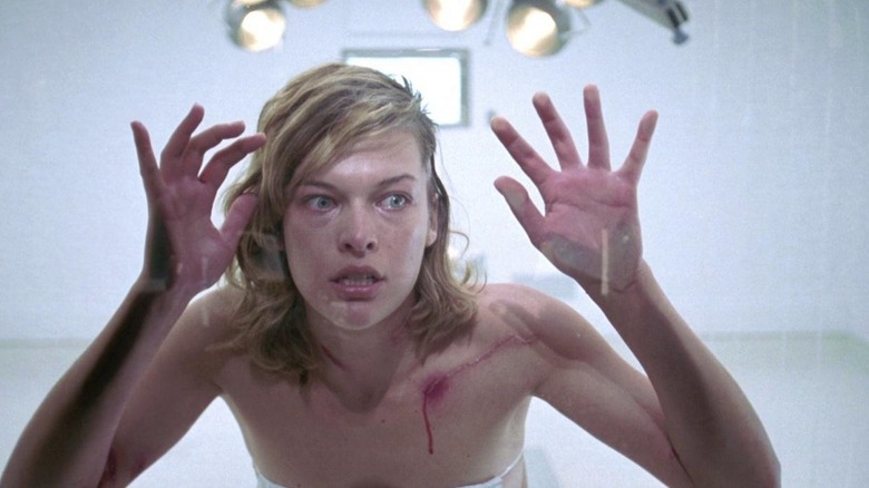 Milla Jovovich as Alice with her hands pressed up against the glass in Resident Evil
