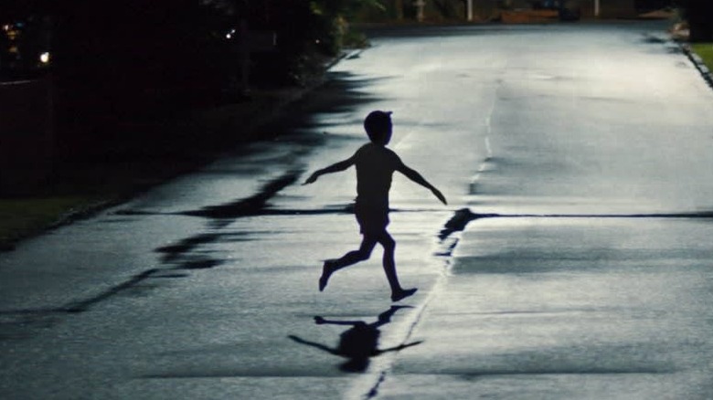A kid running through the road with his arms held out in Weapons