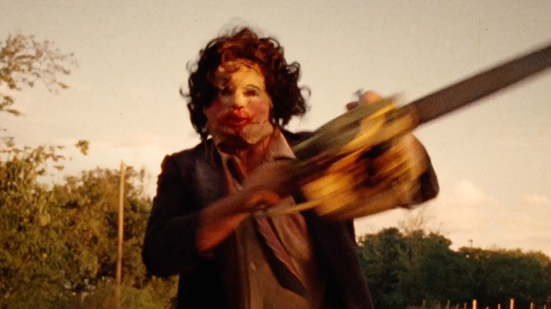 Leatherface running down the street with his chainsaw at the end of The Texas Chain Saw Massacre
