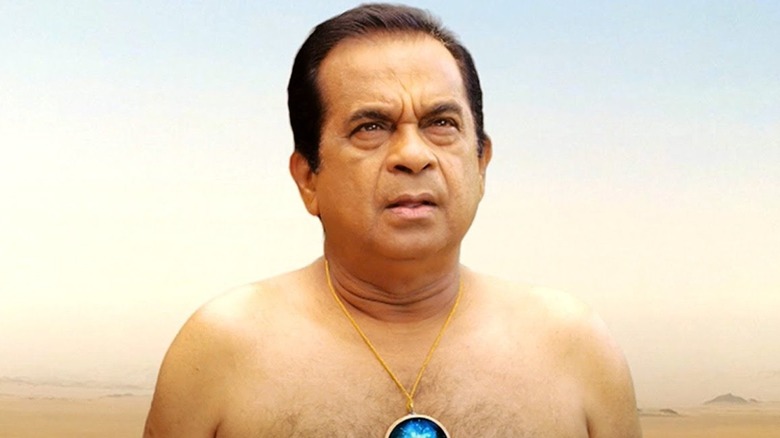 Mr. Google without a shirt standing in a desert, wearing a medallion.