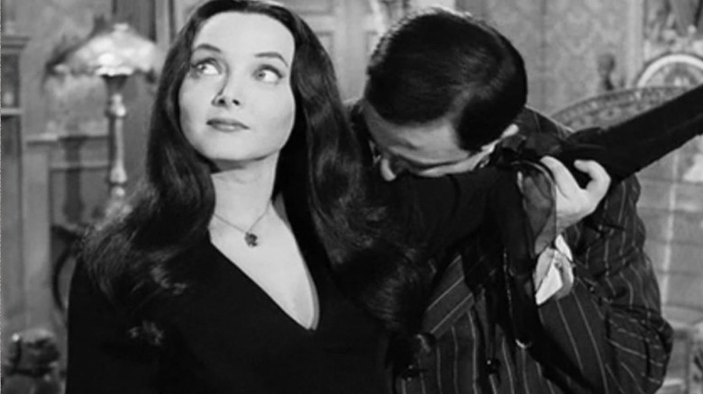Morticia Addams poses next to a chair