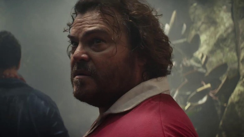 Jack Black as Doug looking over his shoulder in the jungle in Anaconda (2025)
