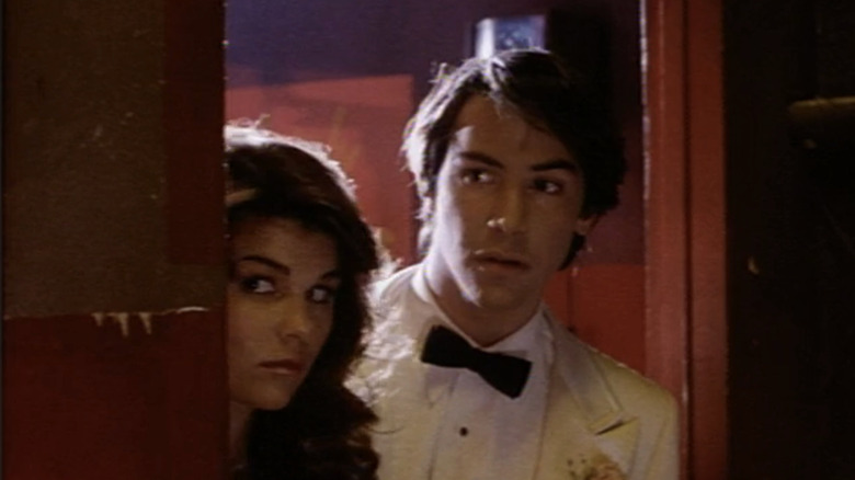 Keanu Reeves as Winston Connelly and Lori Loughlin as Tara Mitchell look out from behind a door frame in The Night Before