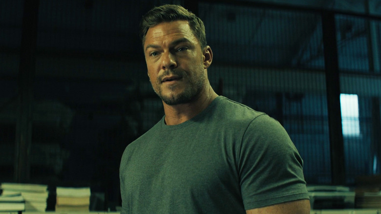 Alan Ritchson's Jack Reacher stands in a warehouse in Reacher