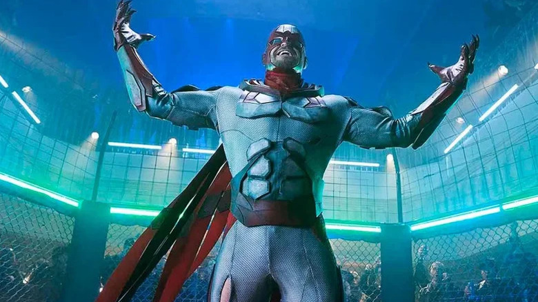 Hank Hawk de Alan Ritchson em pé em um atacante diretamente em titãs