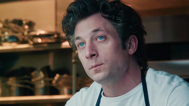 Jeremy Allen White as Carmy Berzatto standing in a kitchen next to some pots in The Bear