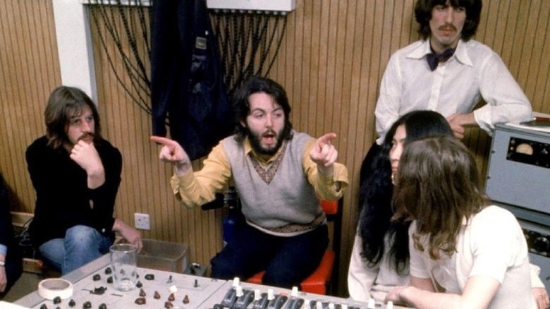 a man pointing to both sides of a room with three men and one woman around him