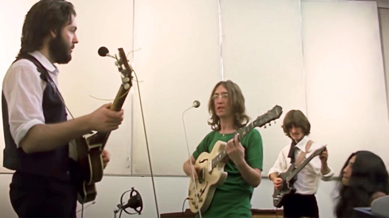 three men playing guitars and a woman sitting down