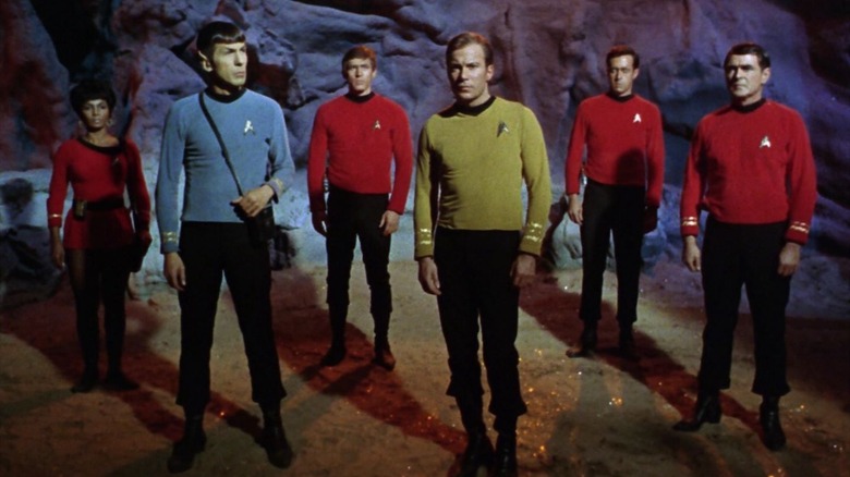 Uhura, Spock, Kirk, Scotty et deux Redshits alignés sur Star Trek