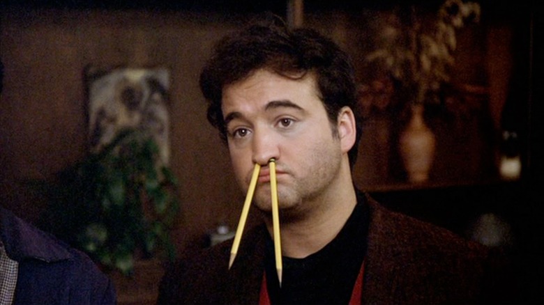 John Belushi as John "Bluto" Blutarsky in Animal House, looking blase with pencils sticking out of his nostrils.