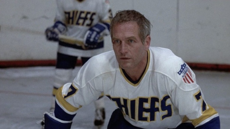Paul Newman as Reggie Dunlop in Slap Shot, in his hockey uniform and slightly crouching down on the ice.