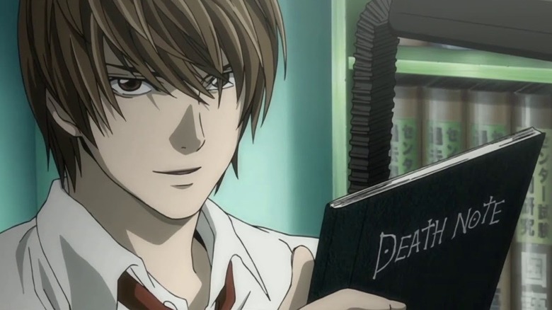 Light Yagami smiles while holding the Death Note in Death Note