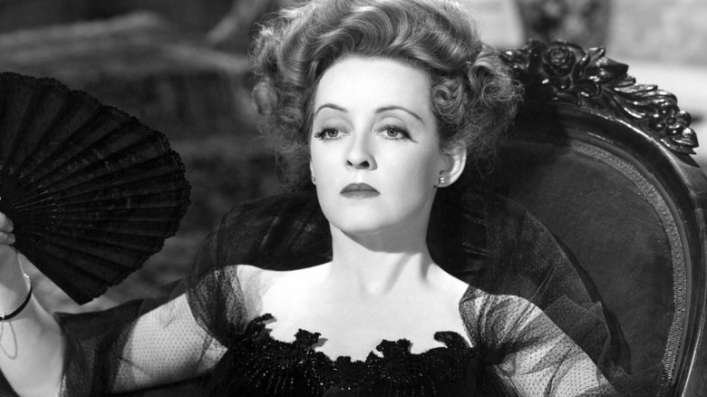 Bette Davis angrily holding fan