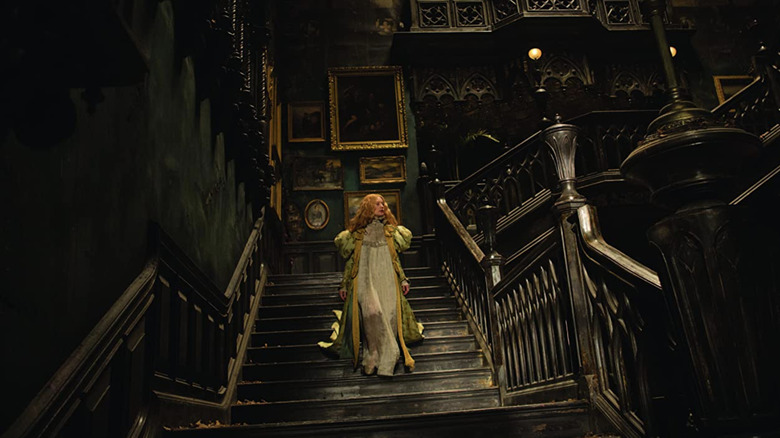 Edith going down the stairs of the mansion