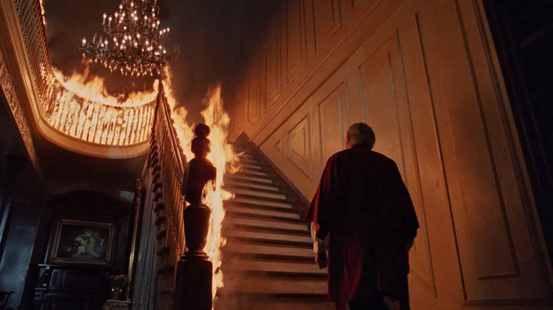 Melvyn Douglas as Senator Joseph Carmichael ascends a burning staircase in The Changeling