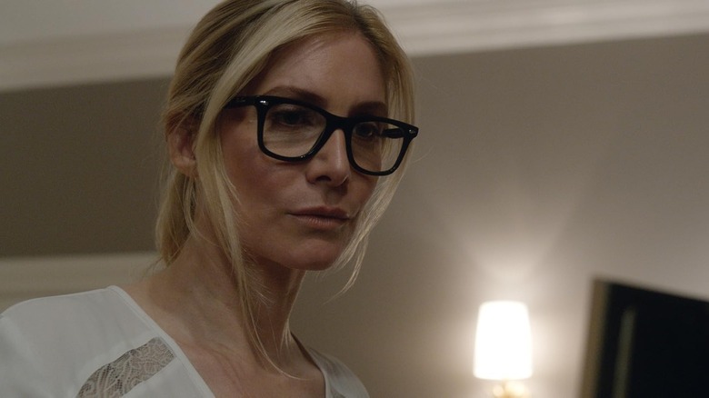 Elizabeth Mitchell as Senator Roan wearing glasses and looking somber next to a lamp in The Purge: Election Year