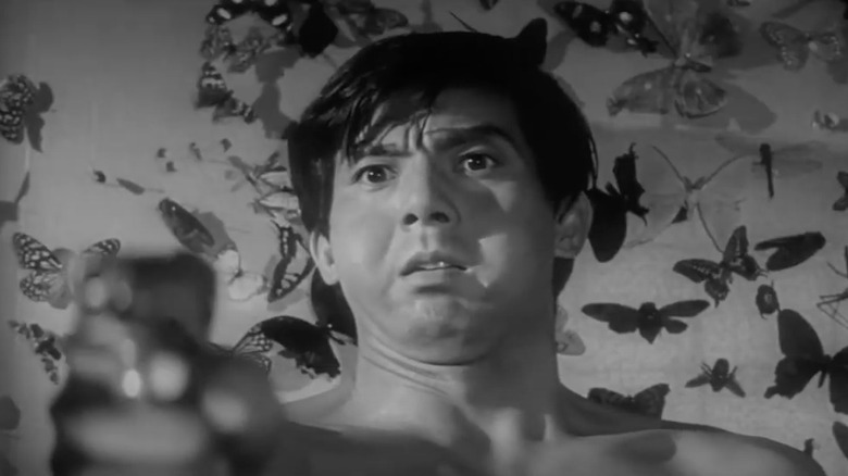 Jō Shishido standing in front of butterflies, pointing gun