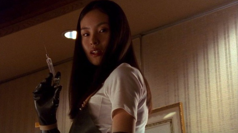 A woman stands up holding a syringe.