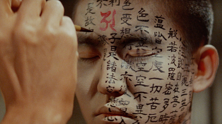 A man in the process of having Japanese characters painted on his face.