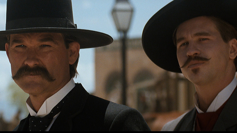 Kurt Russell and Val Kilmer with cowboy hats and moustaches