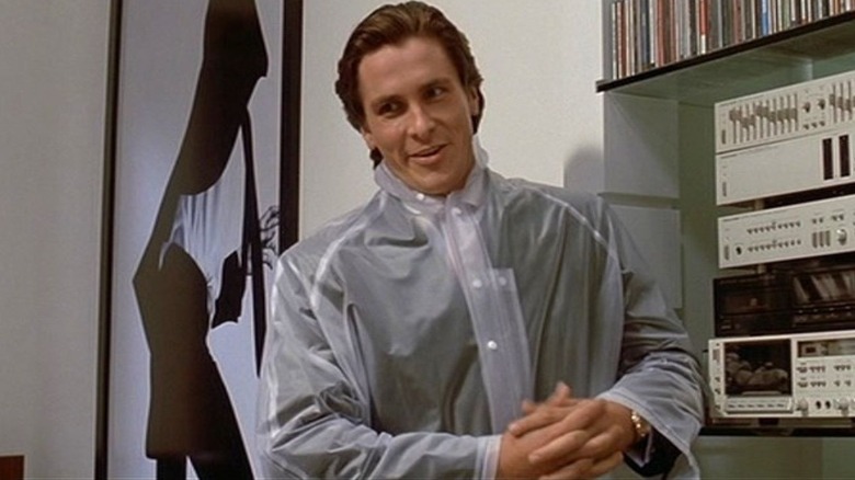 Christian Bale wears a plastic coat as Patrick Bateman who is standing in American Psycho