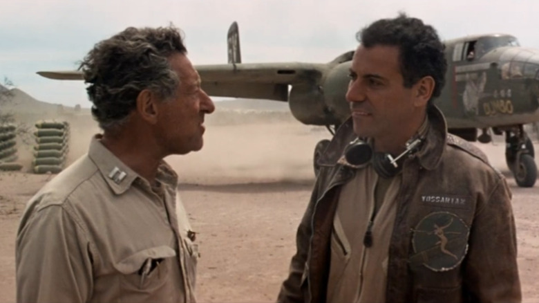 Jack Gilford as Doc Daneeka talks to Alan Arkin as John Yossarian with a plane behind them in Catch-22