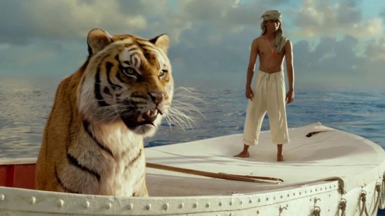 The lion Richard Parker sits on a life boat next to Suraj Sharma as Pi Patel in Life of Pi